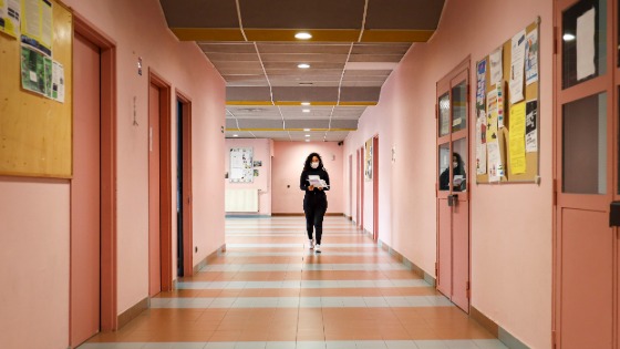 A woman walks down a school hallway