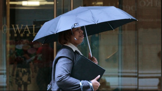 A woman walks through the rain on Wall Street in New York