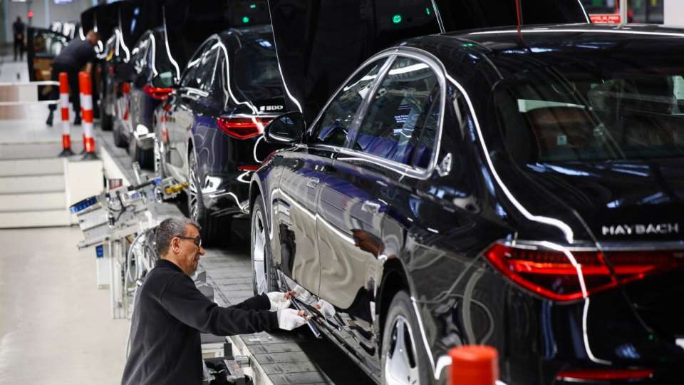 A worker attaches a part to a Mercedes-Maybach car on a production line of _Factory 56,_ one of the worlds most modern electric and conventional car assembly halls of German carmaker Mercedes-Benz