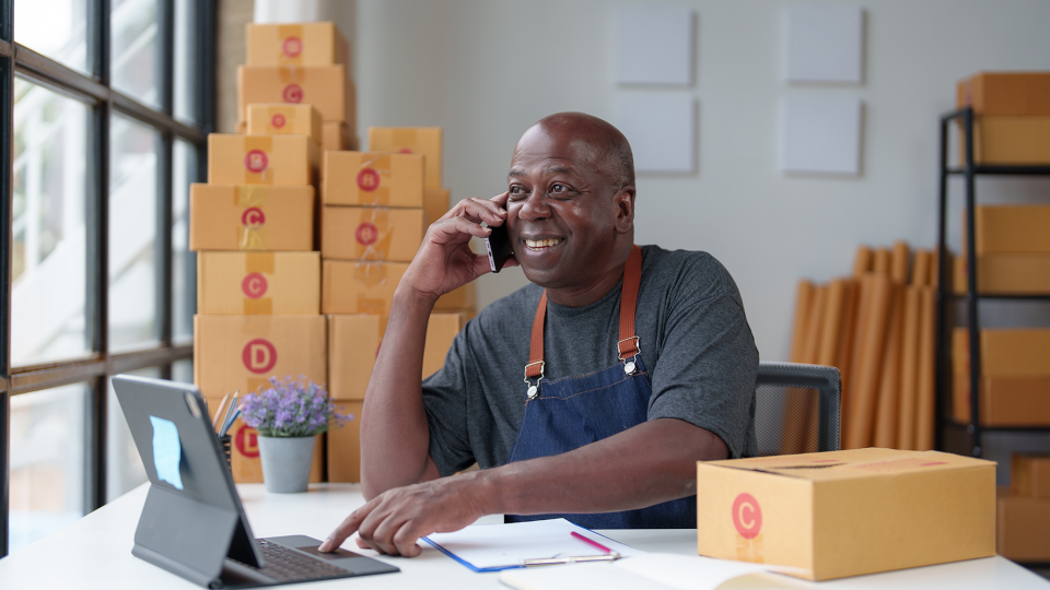 A worker surrounded by boxes talks on the phone 