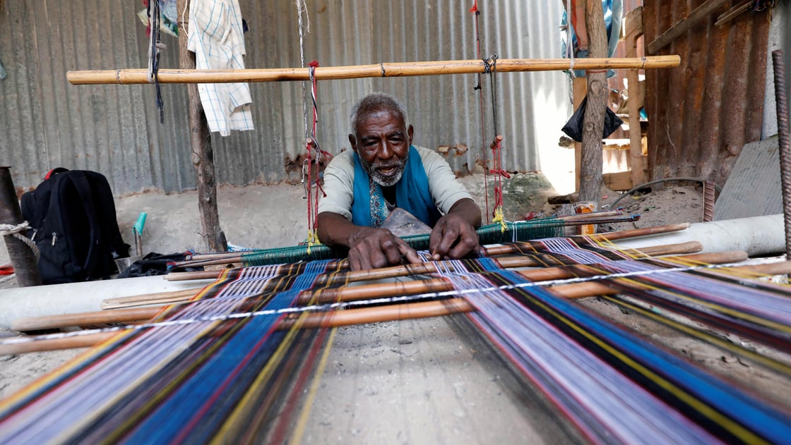 Abdulahi Abuker weaves threads into traditional garments, preserving a Somali tradition that is under threat from a flood of inexpensive clothes imported from China and other countries, in the Madina