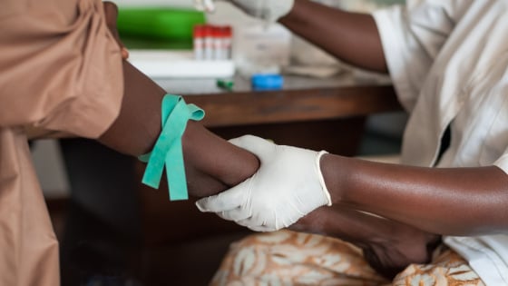 African nurse draws blood from male for blood tests.