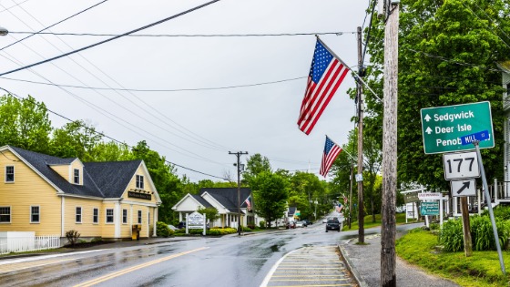 American flag on city main street in Maine during rainy cloudy weather