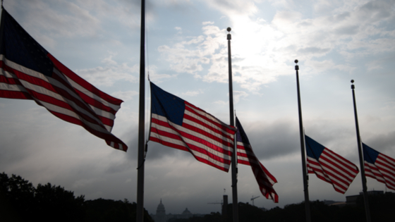 American flags fly at half staff near the Washington Monument with the U.S. Capitol Building