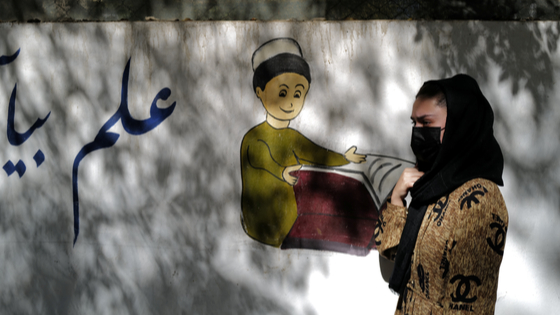 An 11th grade secondary school student, walks past her former school in Kabul, Afghanistan