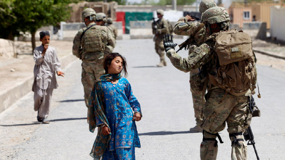 An Afghan girl walks past a U.S soldier on patrol in Kandahar province