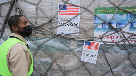 An Ethiopian Airlines Cargo terminal worker looks on as he offloads a shipment of Johnson & Johnson vaccines