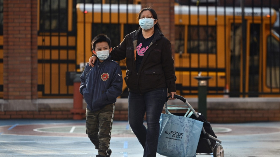 An accompanied student arrives at P.S. 7 Louis F. Simeone schoolyard in Queens