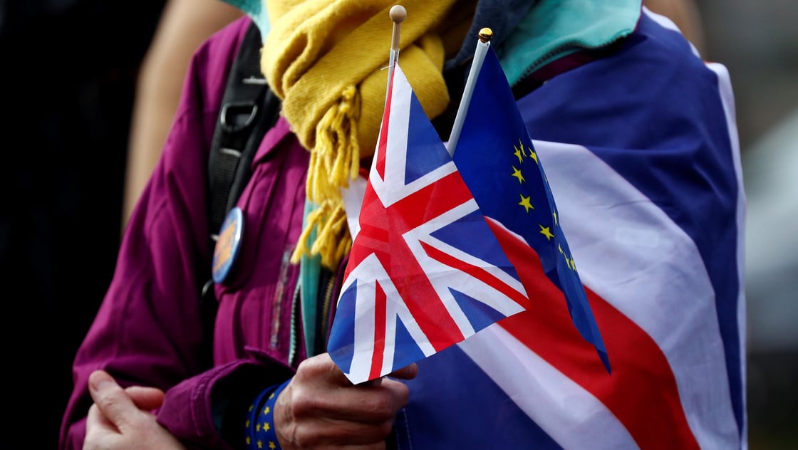 An anti-Brexit demonstrator holds British and European flags during a protest in front of the European Parliament in Brussels