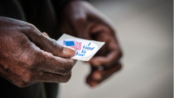 An elderly African American man holds his “I voted” sticker after he cast his ballot in Washington, DC.