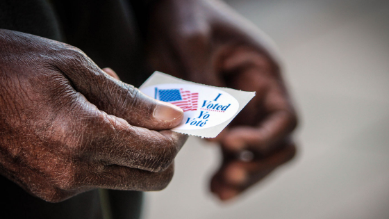 An elderly man holds his voting sticker after he cast his ballot in Washington