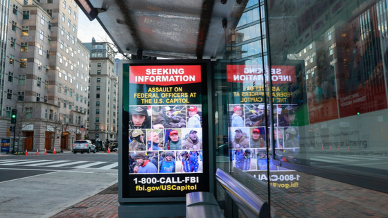 An electronic ad snows the faces of suspects who assaulted federal officers at the Capitol.