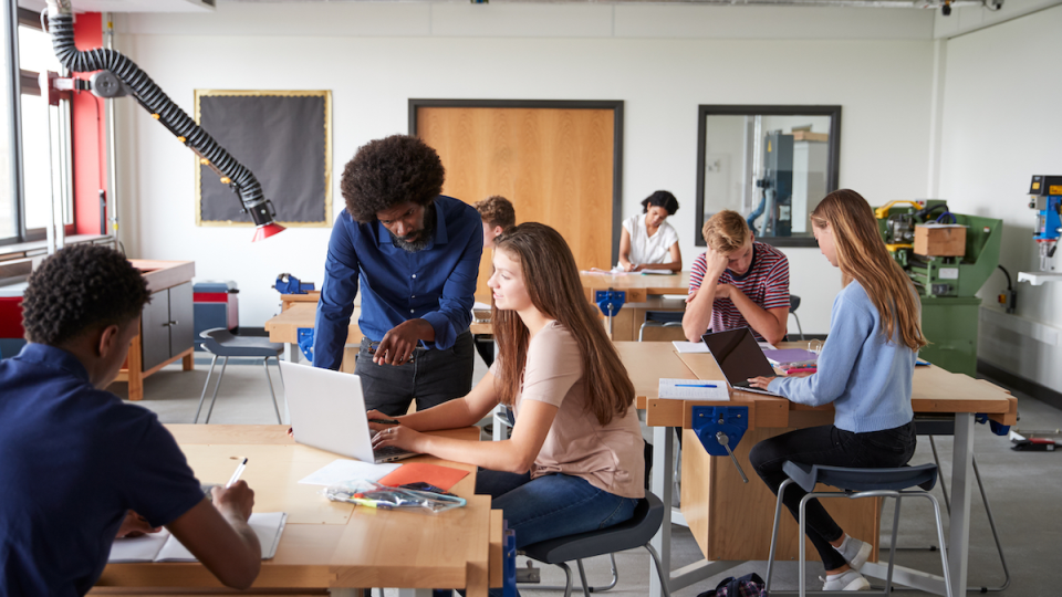 An instructor assists a student in a classroom.