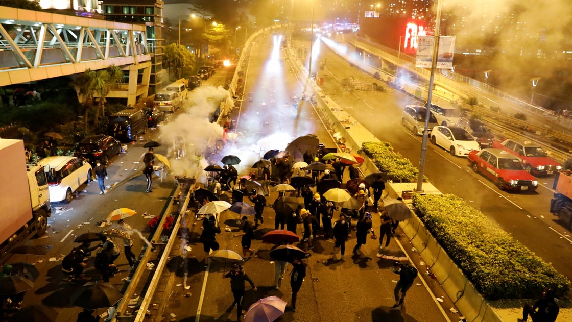 Anti-government demonstrators take cover during clashes with police near the Hong Kong Polytechnic University