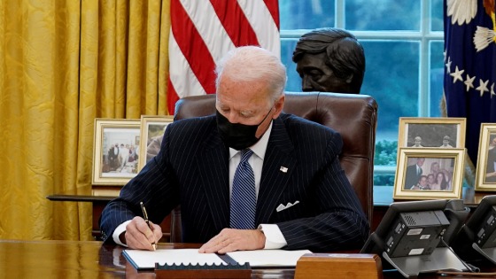 Biden sitting at the resolute desk in the oval office