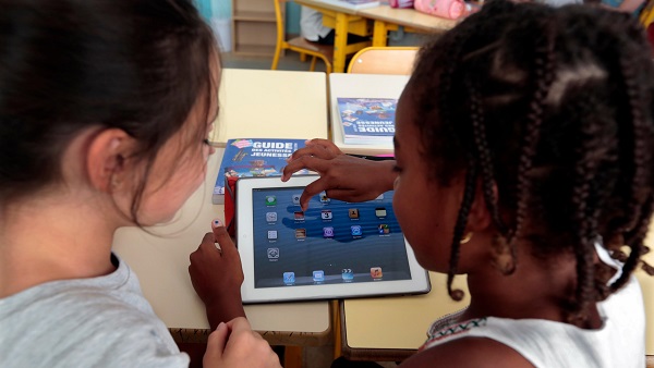 Elementary school children share an electronic tablet on the first day of class in the new school year in Nice, France.