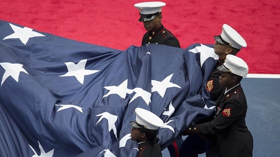 Members of the U.S. Marine Corps gather up a large U.S. flag