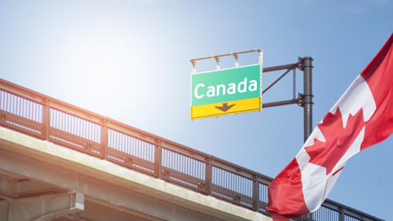 Canada sign on freeway with Canadian flag waving