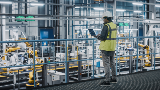 Car factory engineer in high visibility vest using laptop computer