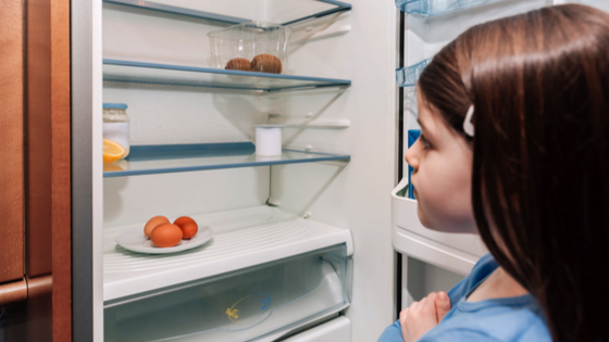 Child looks at empty fridge