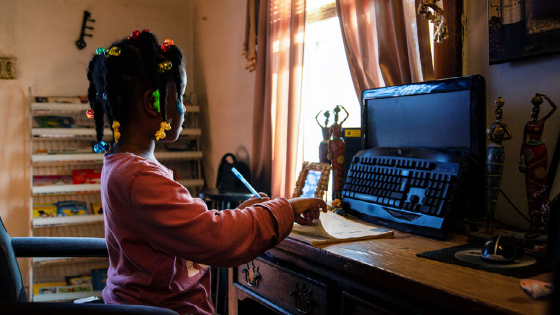 Child looks at turned off computer monitor during remote school