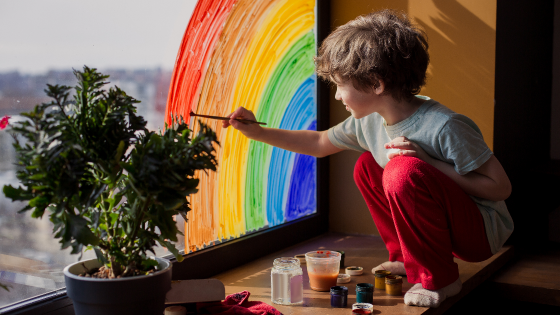 Child paints rainbow on window