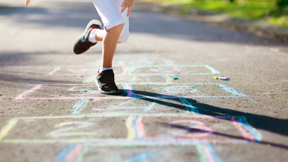 Child plays with game drawn out with chalk