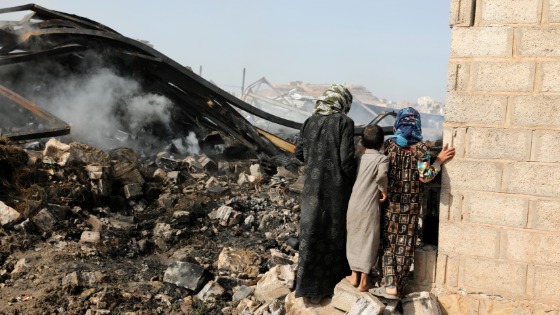 Children look at wreckage of a vehicle oil and tires store