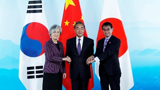 Chinese Foreign Minister Wang Yi, South Korean Foreign Minister Kang Kyung-wha,  and Japanese Foreign Minister Taro Kono shake hands.