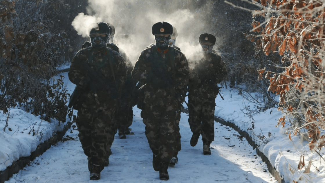 Chinese soldiers walk through snow with equipment