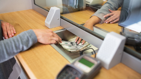 Clerk giving cash money to customer at bank