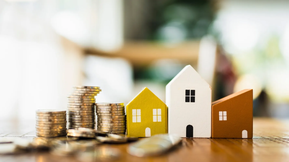 Coins with toy houses on table