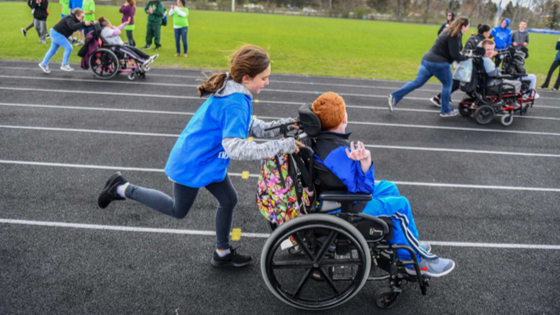 Competitors in wheelchairs get some assistance around the track during the Developmental Adapted Physical Education track meet.