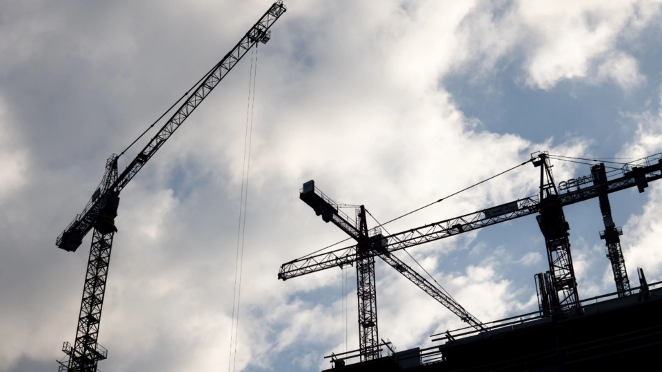 Construction cranes against a cloudy sky