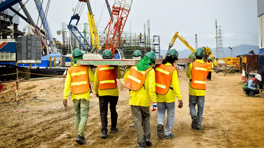 Construction workers carrying wooden plank