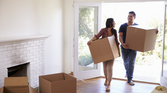 Couple carries boxes into new house