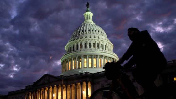 Cyclist goes past the Capitol on a cloudy evening