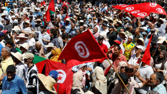 Demonstrators hold flags as they gather during a protest against Tunisian President Kais Saied