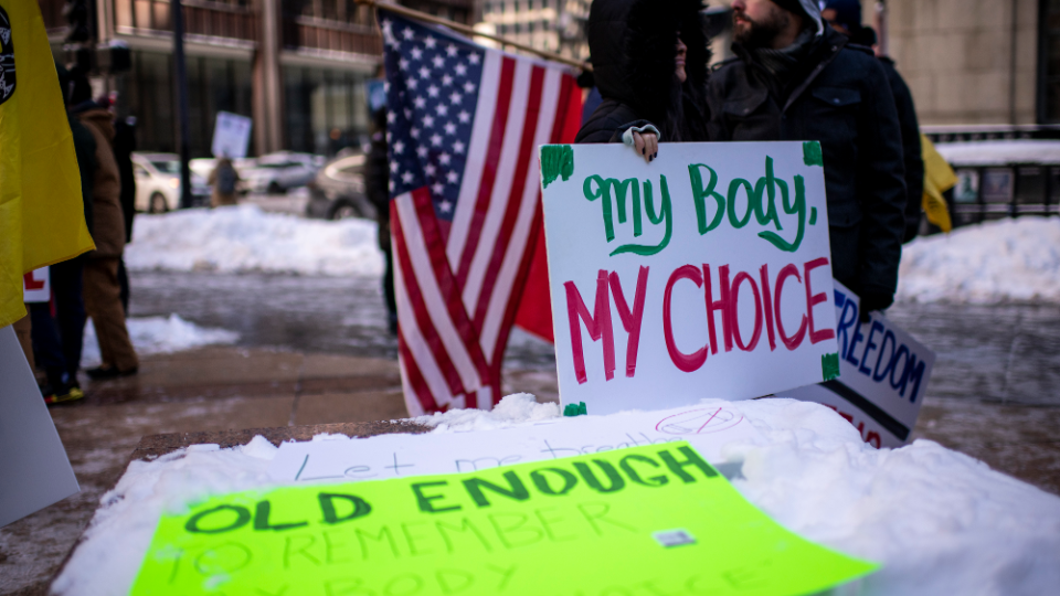 Demonstrators hold signs and American flags during rally in opposition to COVID-19 vaccine and mask mandates in Chicago