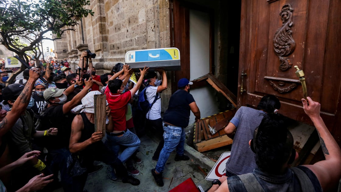 Demonstrators smash down a door of the Jalisco State Government Palace during a protest to demand justice for Giovanni Lopez