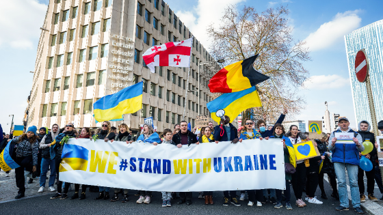 Demonstrators wave the national flags of Ukraine, Georgia, and Belgium during the demonstration