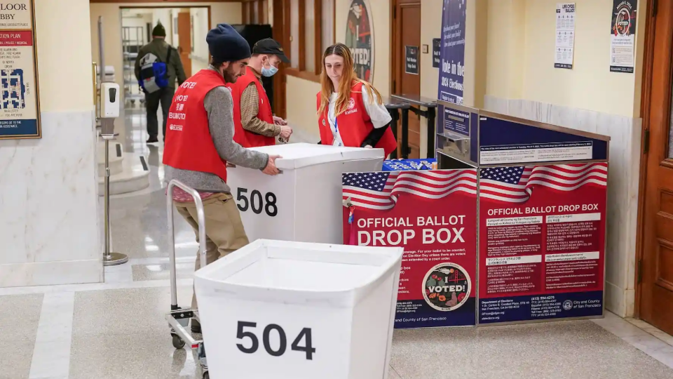 Department of Elections workers transport a box of ballots at the San Francisco City Hall voting center