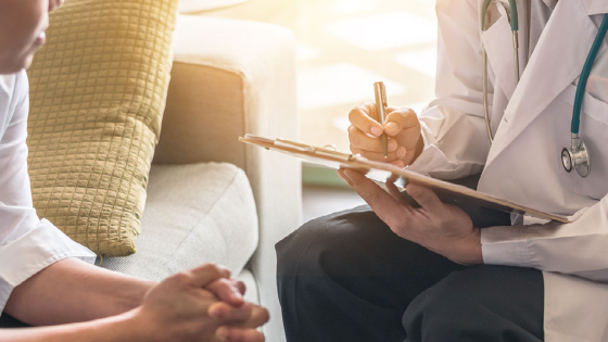 Doctor takes notes while meeting with patient