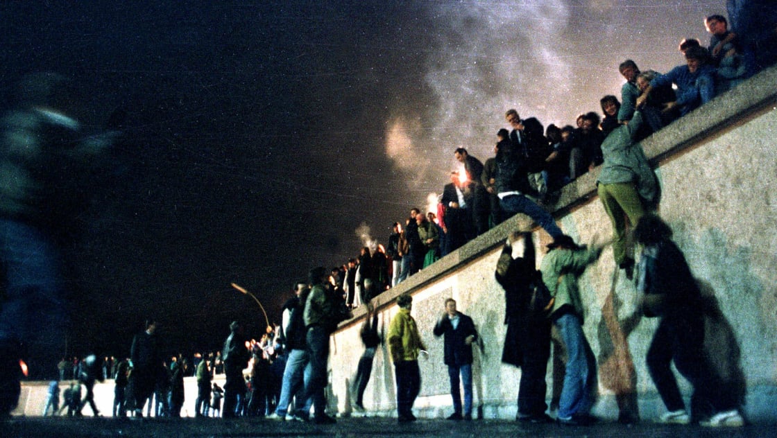 East German citizens climb the Berlin wall at the Brandeburg gate after the opening of the East German border was announced, November 10, 1989