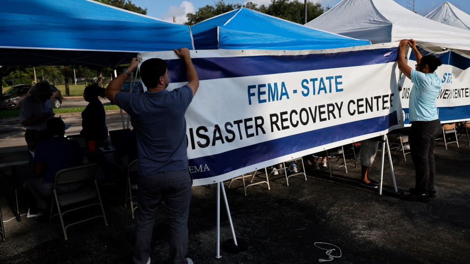 FEMA employees hang a banner at a Disaster Recovery Center on May 12, 2023, in Hollywood, Florida
