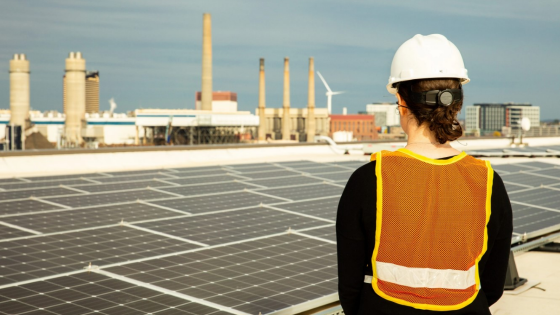 Female solar installer inspecting a commercial rooftop solar system in Charlestown