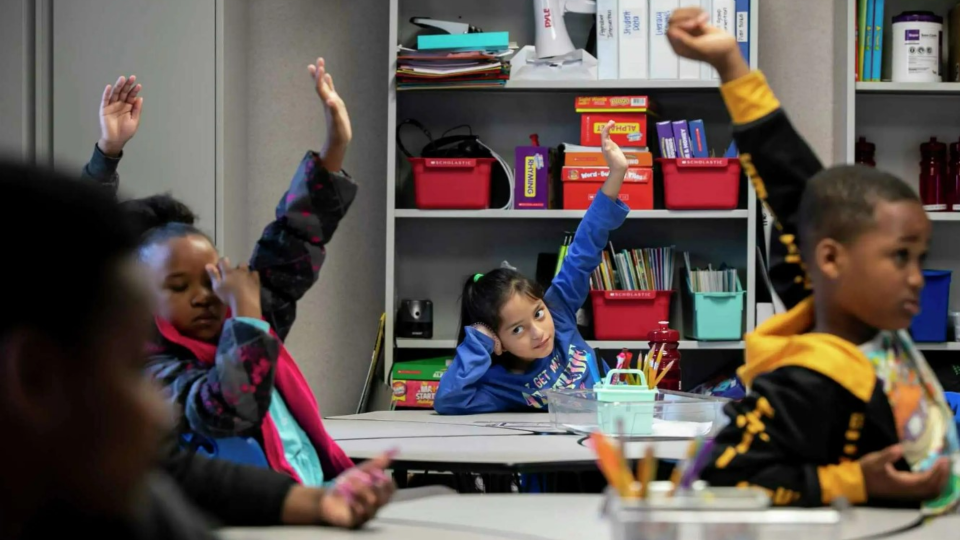 First graders raise their hands to ask questions while learning about the water cycle at Essence Preparatory Public School in San Antonio