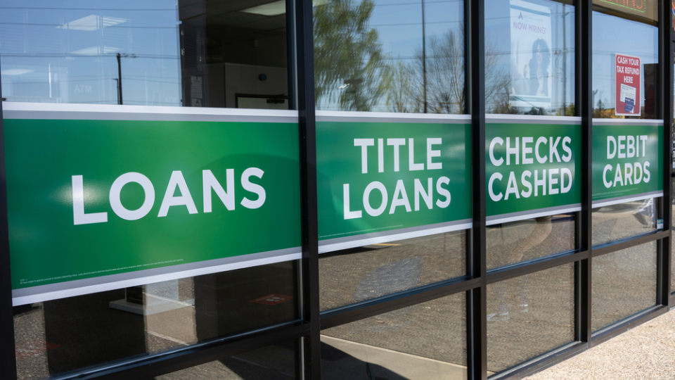 Front of check cashing business with signs for loans and debit cards.