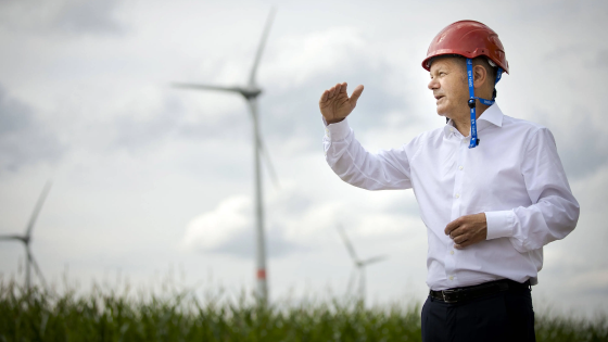 German Chancellor Olaf Scholz talking with windmills in the background