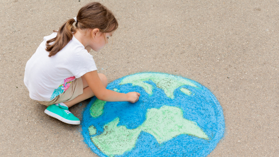 Girl student draws the planet Earth with chalk.